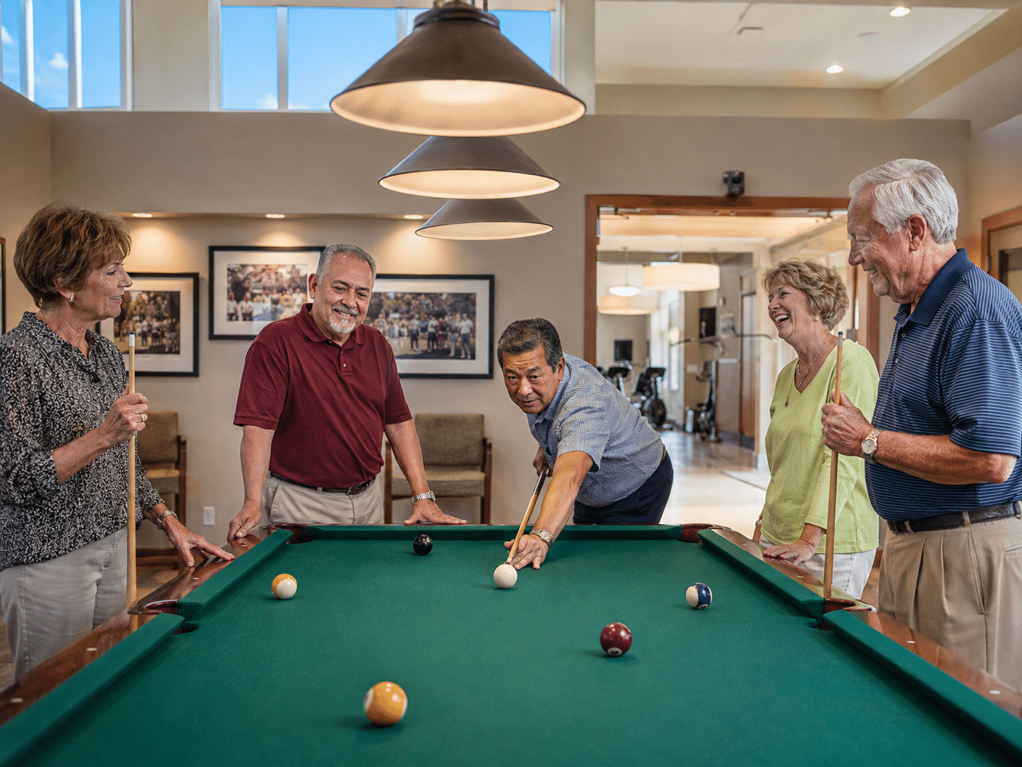 Group of 55+ residents at billiards table inside Ventana Lakes clubhouse Peoria AZ social club midday